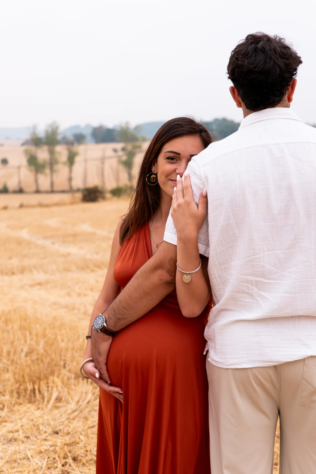 Une future mère adresse un regard tendre par-dessus l’épaule de son compagnon.