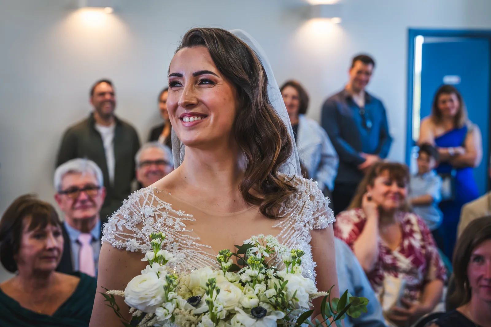 La mariée rit pendant la cérémonie, son bouquet posé contre elle.